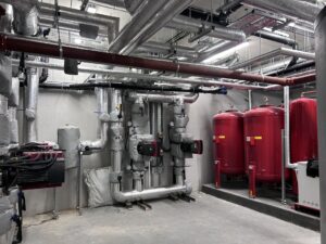 Heating pipework header insulated with foiled fiberglass and clad with aluminium, valves and circulation pumps jackets fitted