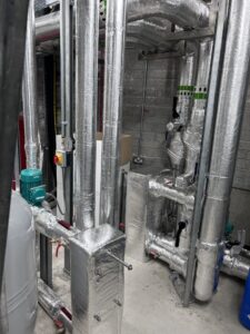 Industrial pipework with isolation valves, pumps and heat exchanger insulated with foiled fiberglass by Lagforce